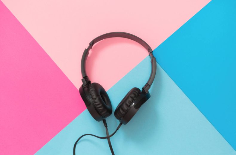 Modern style black headphones on the pink blue background. Top view.